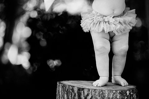 Black and white close-up portrait of a baby standing during a one-year milestone session
