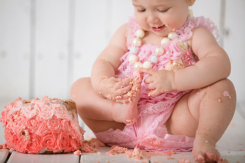 Baby girl enjoying a pink cake smash during a first birthday photography session
