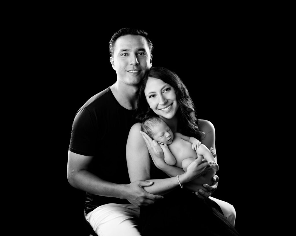 Parents holding their sleeping newborn baby during a black and white family portrait