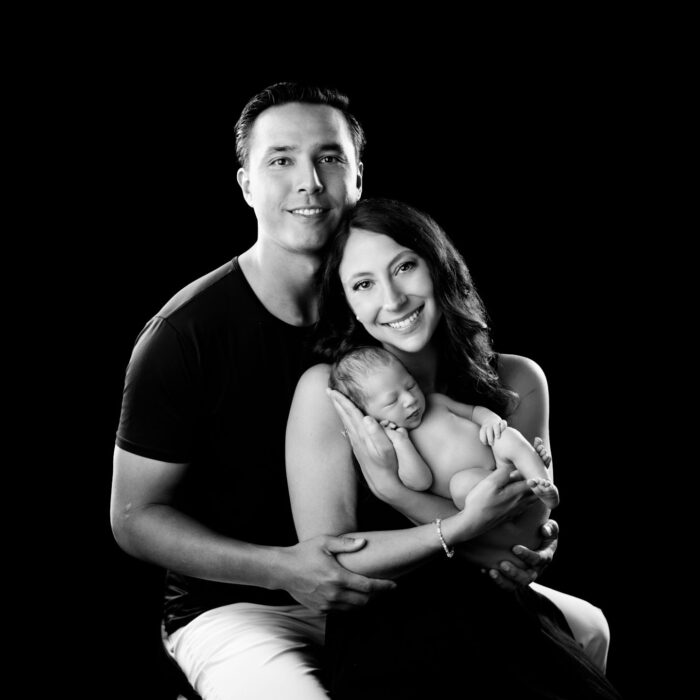 Parents holding their sleeping newborn baby during a black and white family portrait