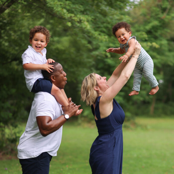Parents playing with young children during outdoor family portrait session.