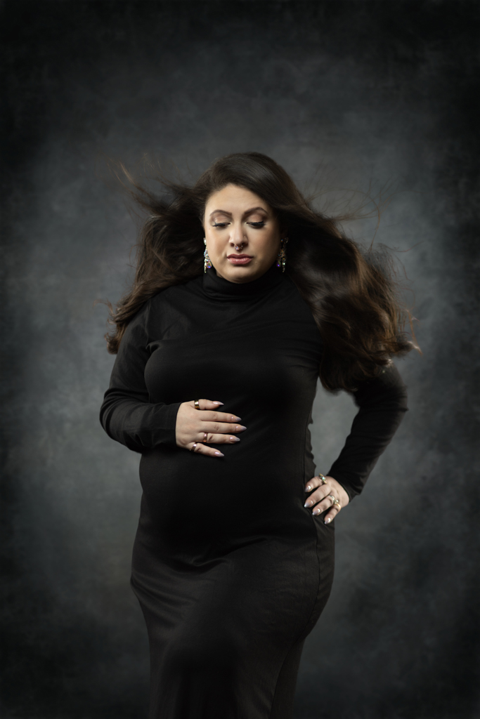 Expectant mother in black maternity gown posing in a Norwood MA photography studio