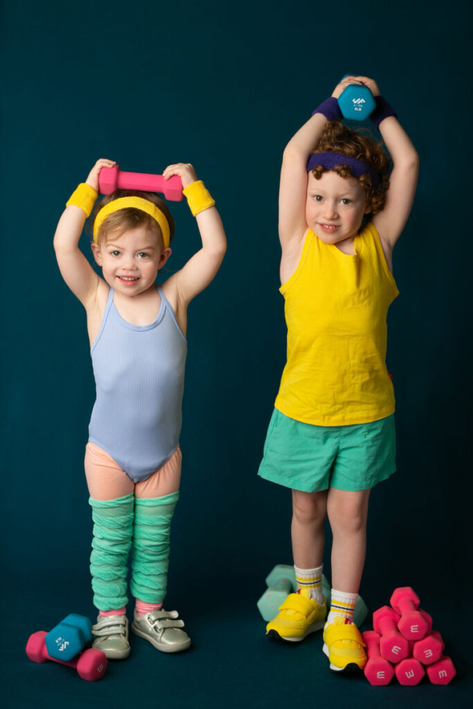 Young siblings posing with colorful exercise weights during creative portrait session.