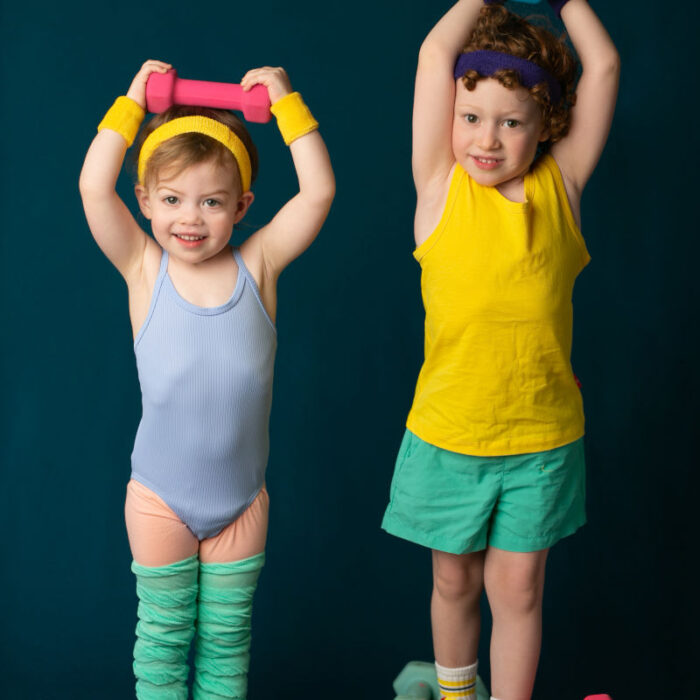 Young siblings posing with colorful exercise weights during creative portrait session.
