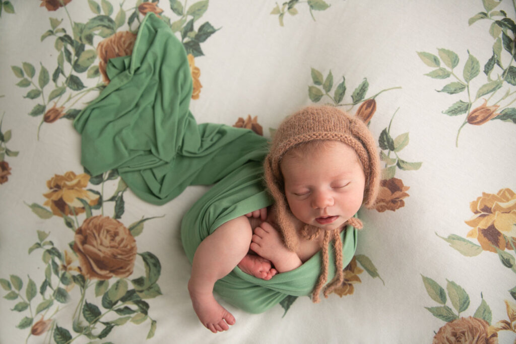Sleeping newborn wearing a knit bonnet during a floral newborn photography session
