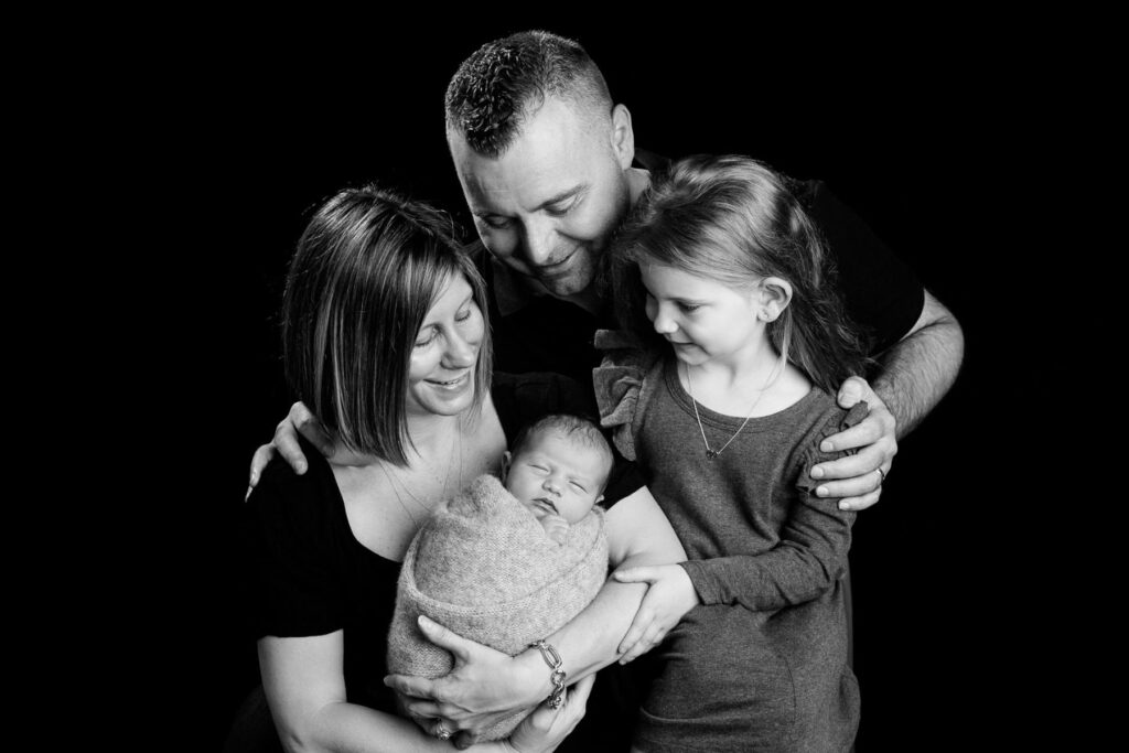 Family portrait with parents, newborn baby and excited older sister during a newborn session