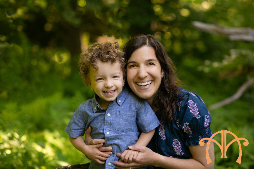 Mother holding smiling young son during outdoor family photography session in natural light