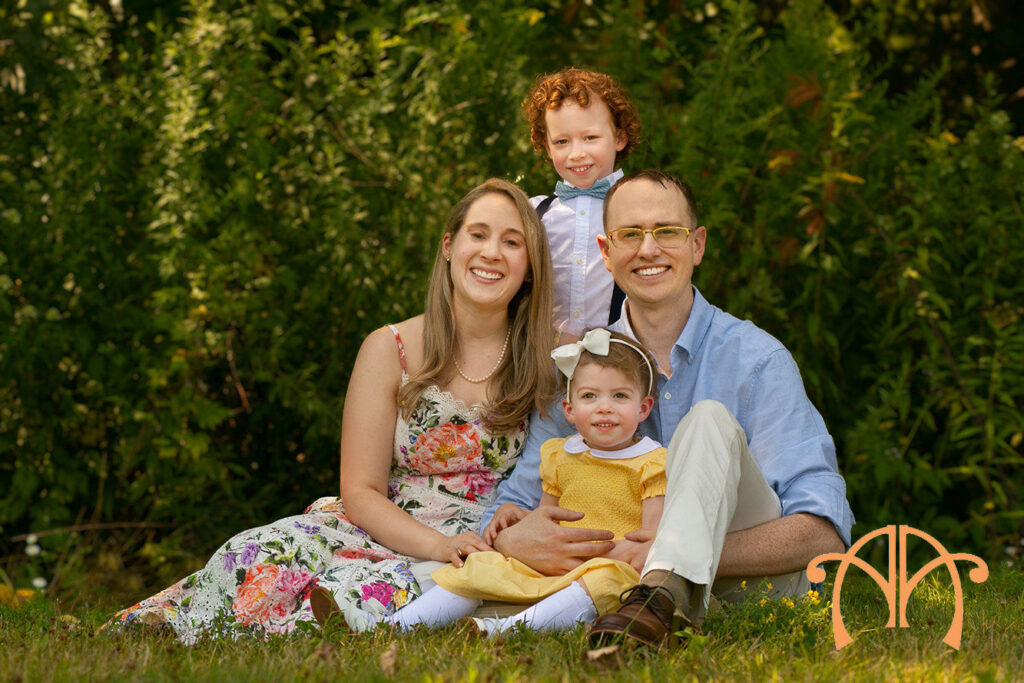 Family of four sitting outdoors with young children during a family photography session