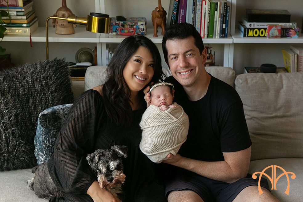 Parents holding newborn baby with family dog during in-home newborn photography session