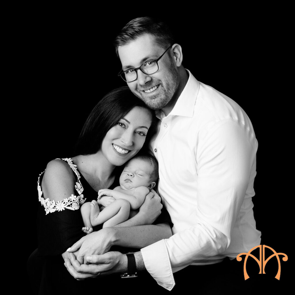 Black-and-white portrait of parents holding newborn baby during studio photography session
