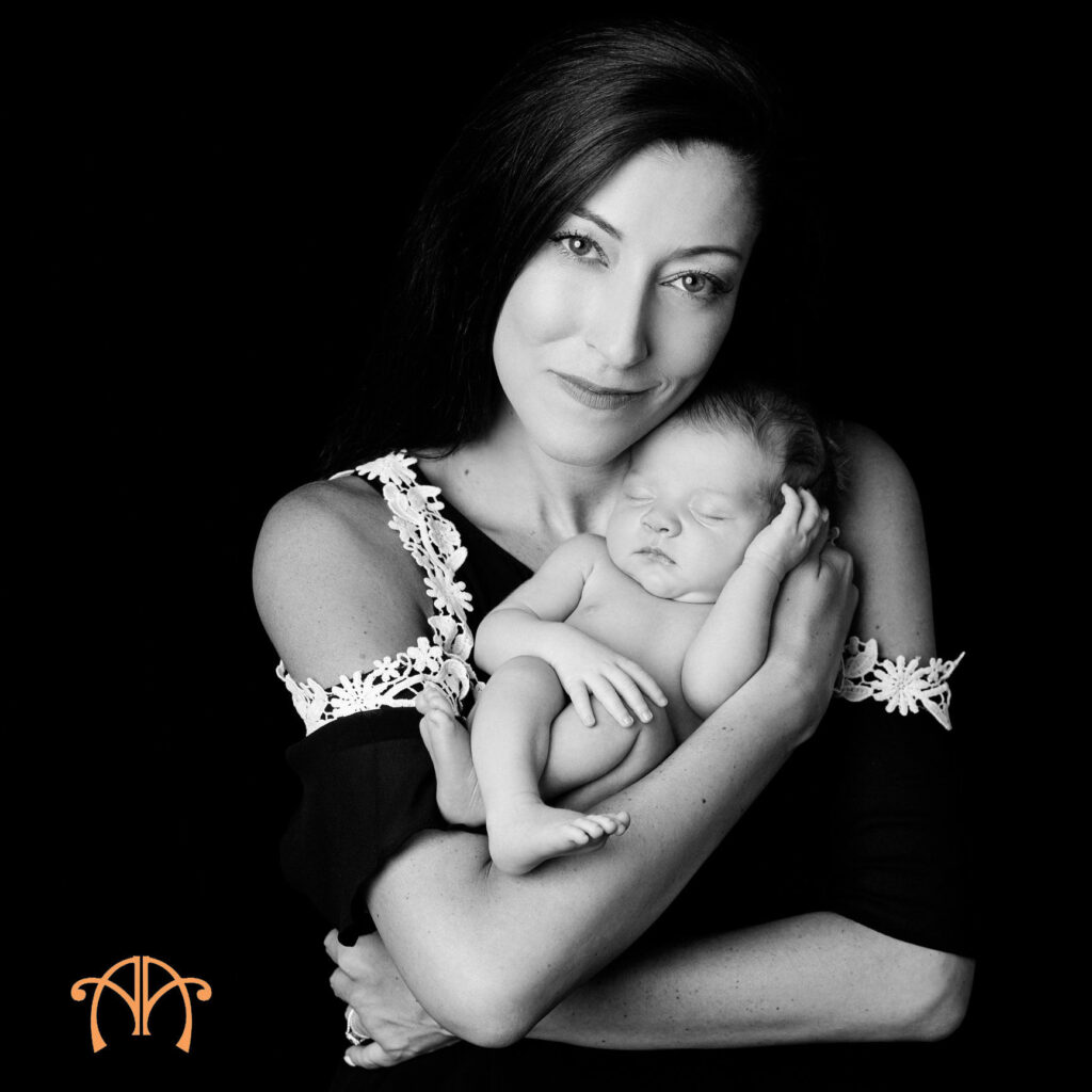 Mother holding sleeping newborn baby during black-and-white newborn photography session