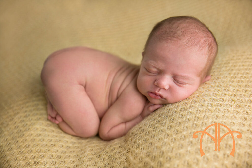 Sleeping newborn baby girl posed on a soft yellow blanket during a studio newborn photography session