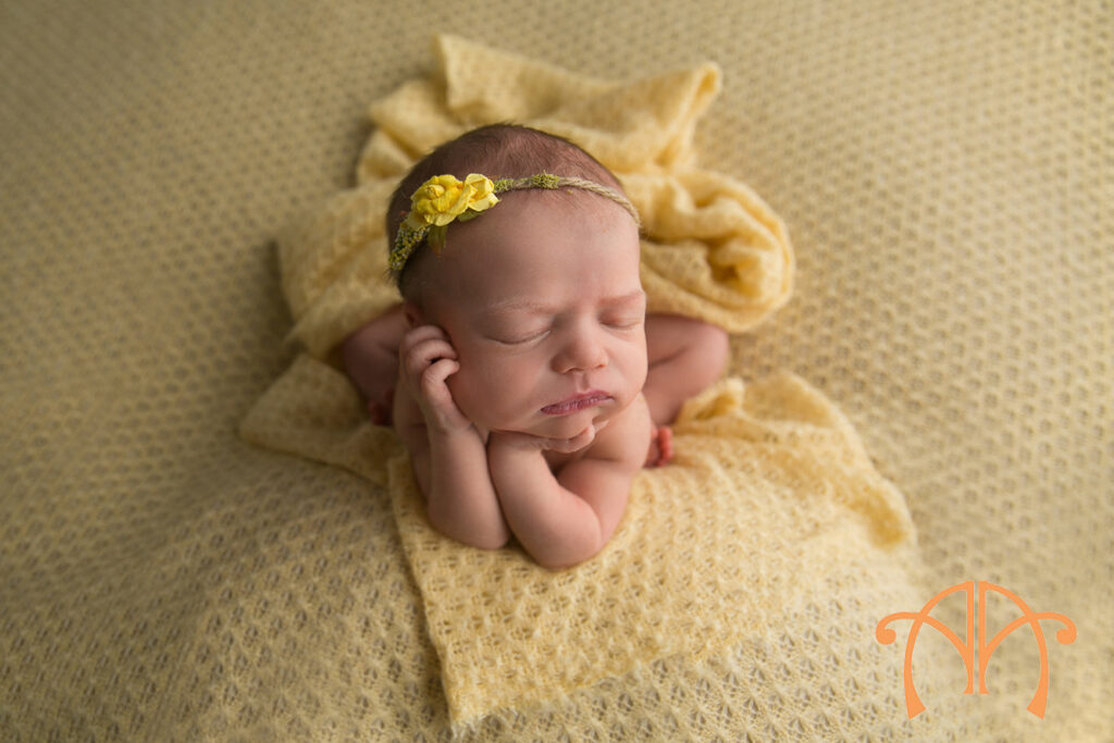 Sleeping newborn baby girl wearing a yellow knit bonnet during professional newborn session