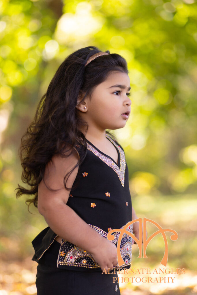 Four-year-old girl in a black traditional dress photographed outdoors during a fall child portrait session