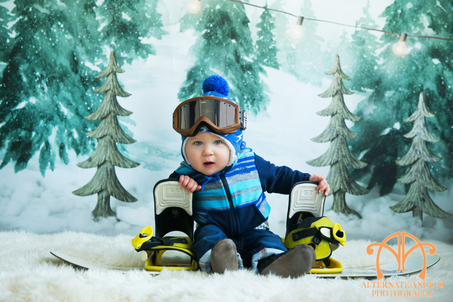 Baby wearing winter clothing and ski gear during a themed milestone portrait session