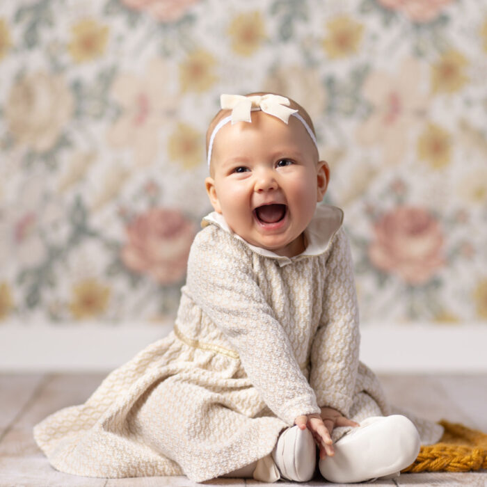 Smiling baby girl during a sitting milestone portrait session in the photography studio