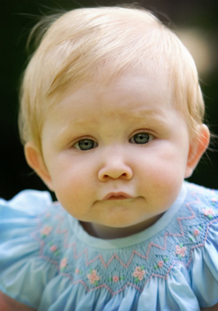 Close-up outdoor portrait of a baby girl with soft natural light and calm expression