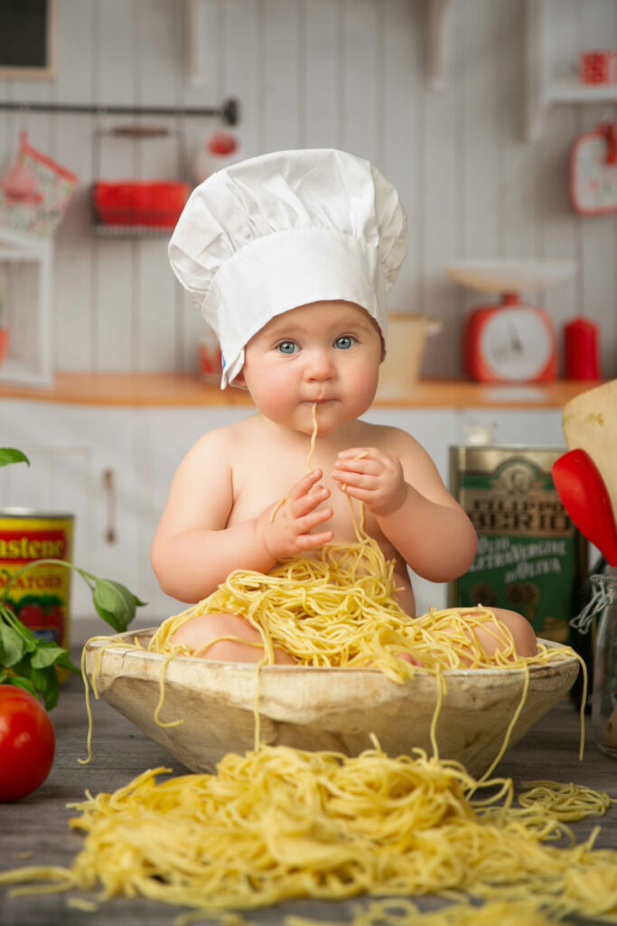 Baby enjoying a playful spaghetti-themed six month milestone portrait session in the studio