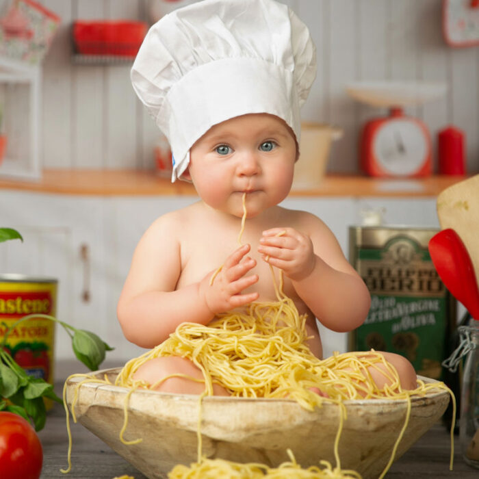 Baby enjoying a playful spaghetti-themed six month milestone portrait session in the studio