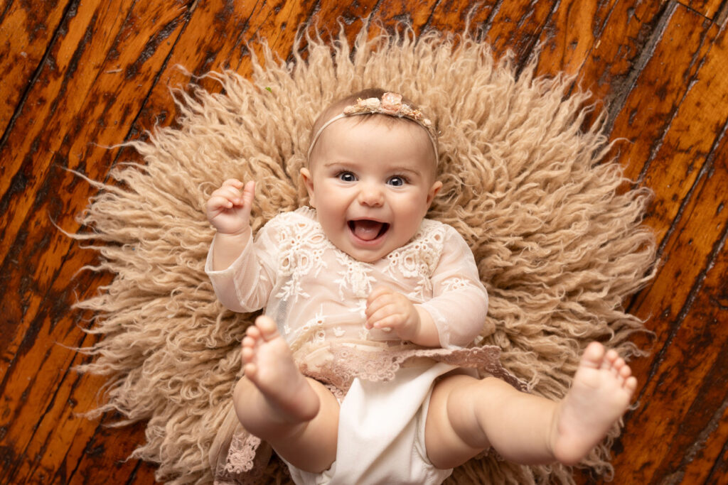 Laughing six month old baby girl during milestone photography session