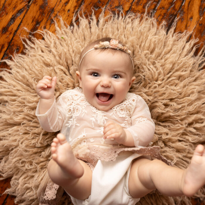 Laughing six month old baby girl during milestone photography session