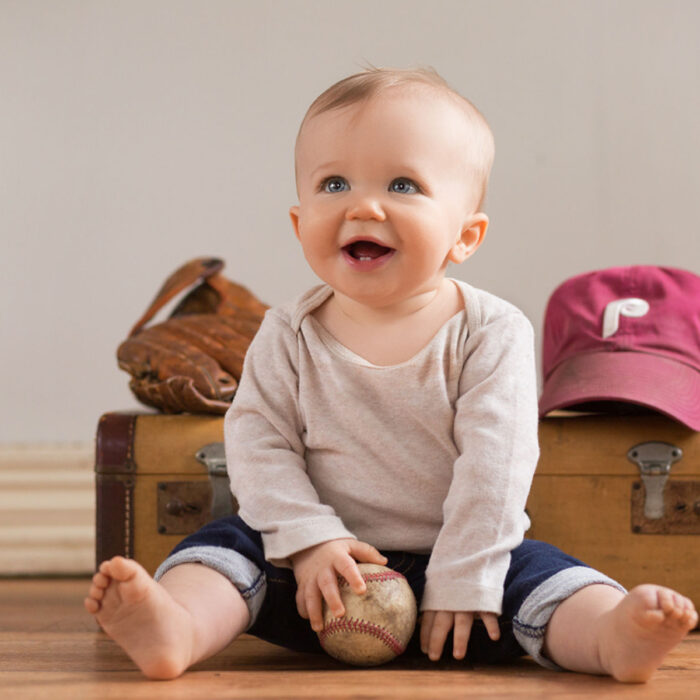 Baby boy holding baseball during sports themed milestone portrait session