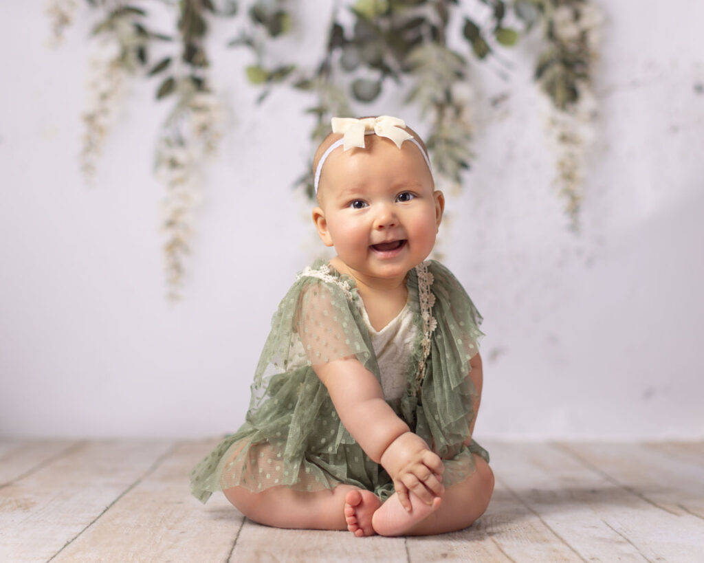 Baby girl in green dress during boho inspired milestone photography session