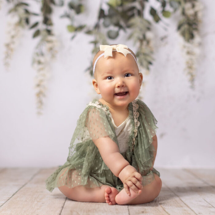 Baby girl in green dress during boho inspired milestone photography session