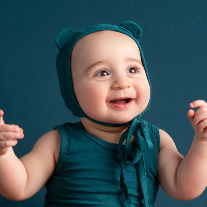 Smiling baby wearing teal bonnet during studio milestone portrait session