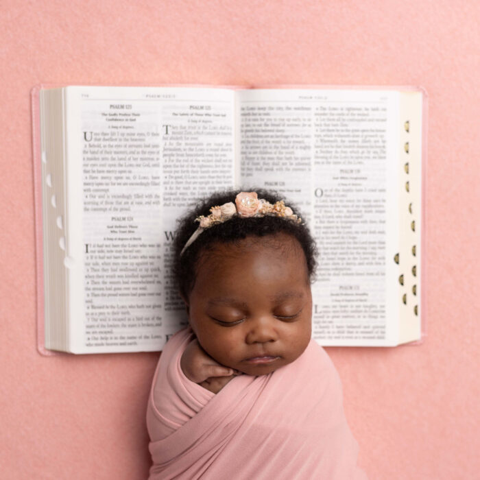 Sleeping newborn baby posed with an open Bible during a faith-inspired newborn photography session.
