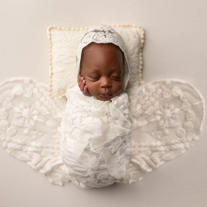 Sleeping newborn baby styled in a butterfly-inspired portrait setup