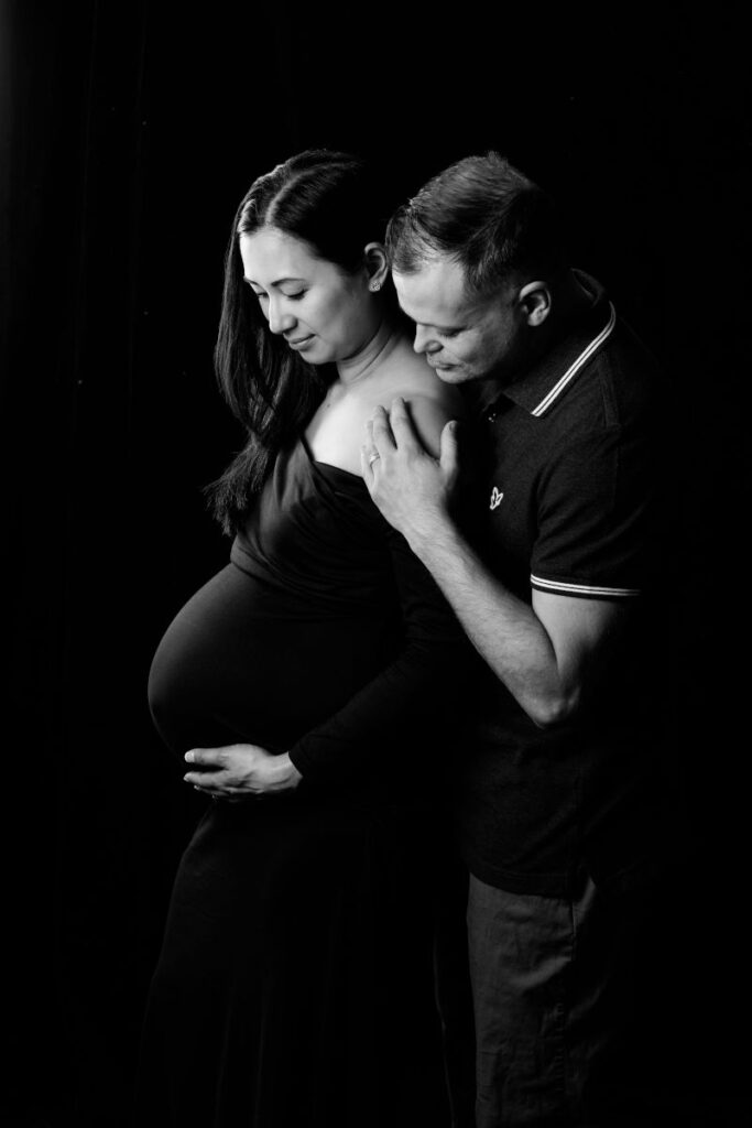 Expecting couple embracing during a classic black-and-white maternity portrait session