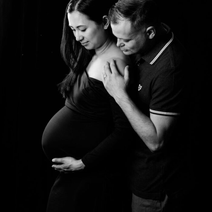 Expecting couple embracing during a classic black-and-white maternity portrait session