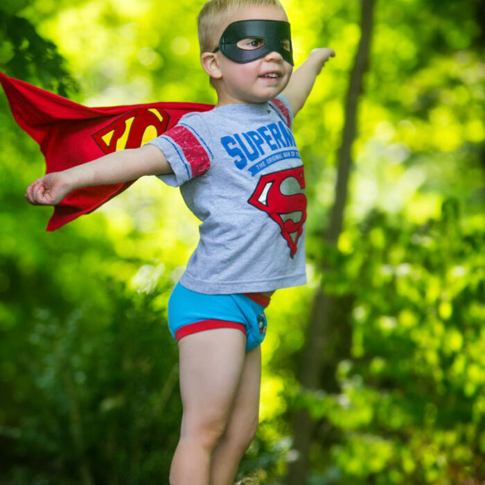 Young child dressed as superhero during outdoor portrait session.
