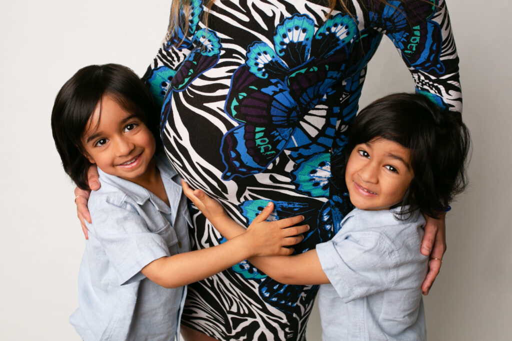 Young brothers hugging their mother's pregnant belly during a family maternity session