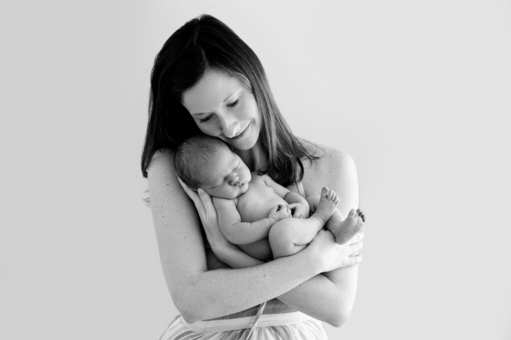 Mother cuddling sleeping newborn baby during studio portrait session
