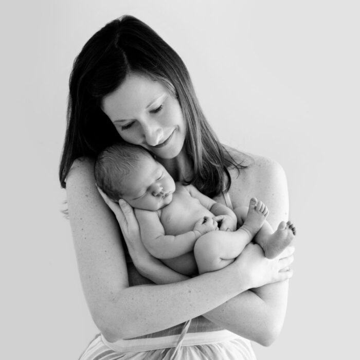 Mother cuddling sleeping newborn baby during studio portrait session