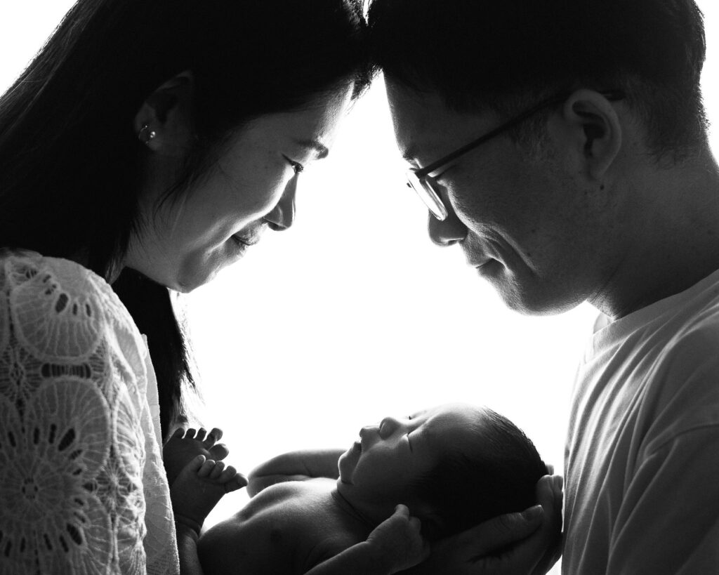 Black and white portrait of parents holding their newborn baby close together