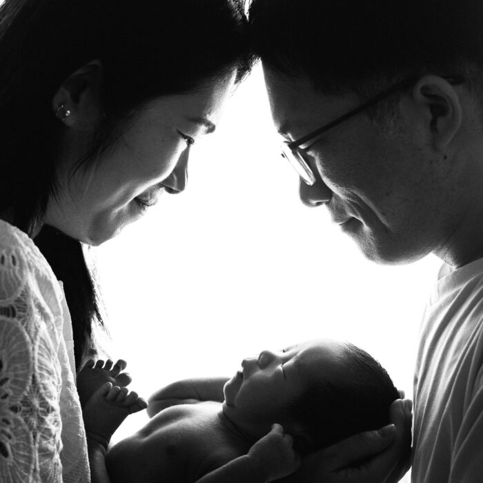 Black and white portrait of parents holding their newborn baby close together