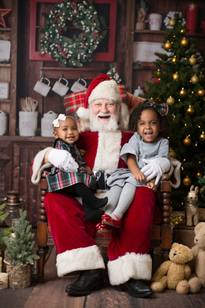 Two young children sitting with Santa during Christmas portrait session