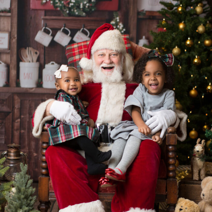 Two young children sitting with Santa during Christmas portrait session