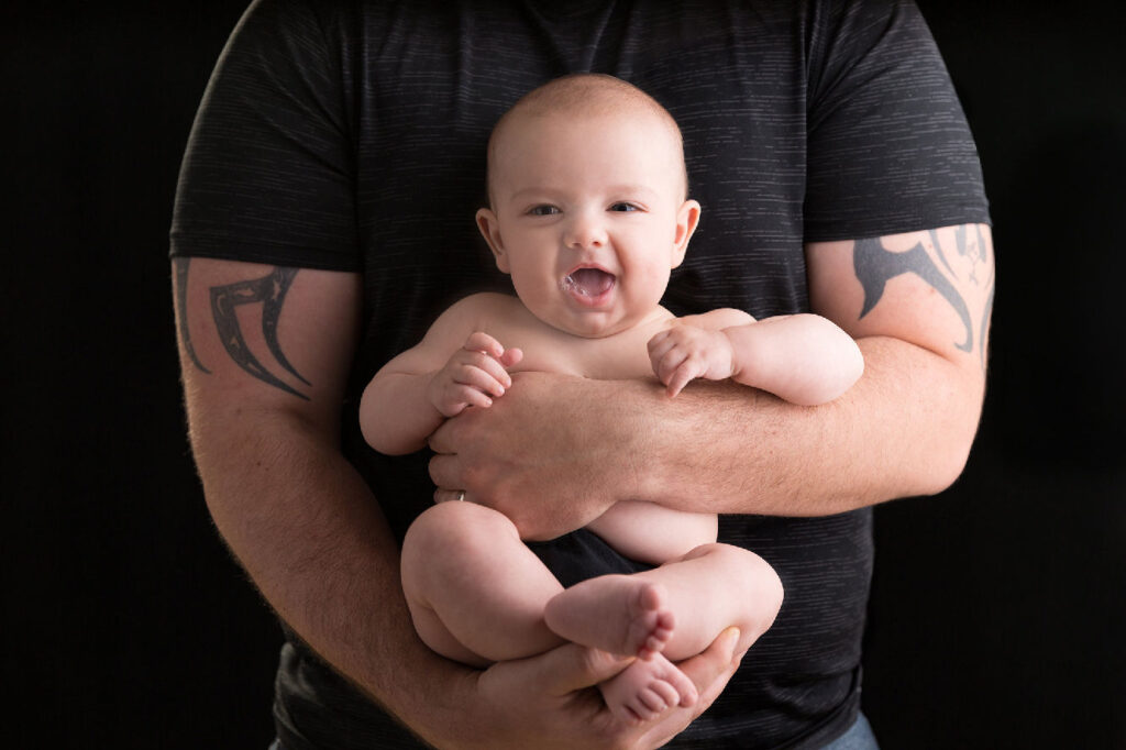 Father holding smiling baby during studio portrait session.