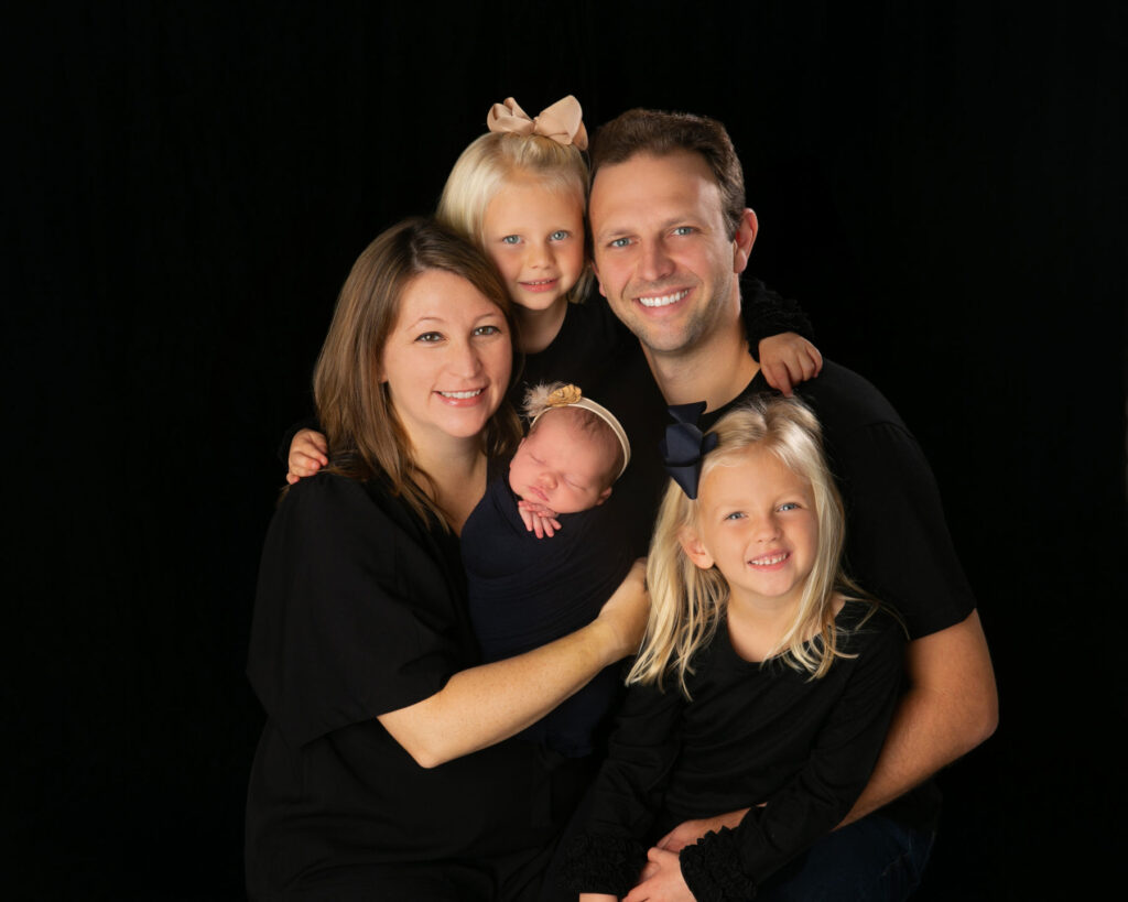 Family portrait with parents, newborn baby, and two young daughters