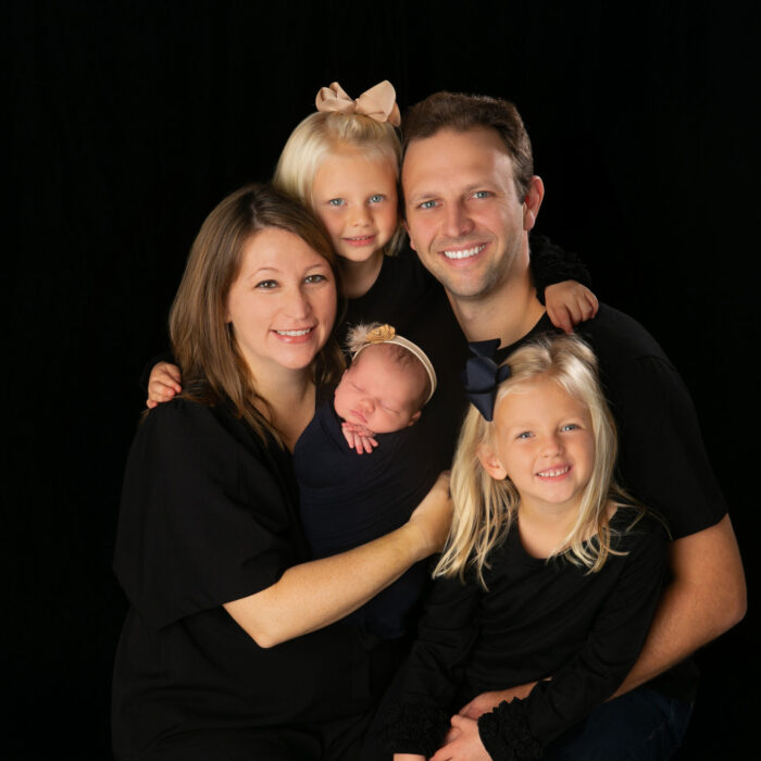 Family portrait with parents, newborn baby, and two young daughters