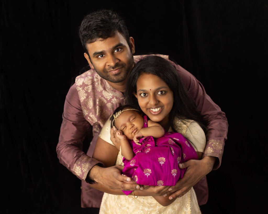 Parents holding their newborn daughter during a studio family portrait session