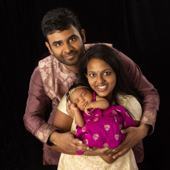 Parents holding their newborn daughter during a studio family portrait session