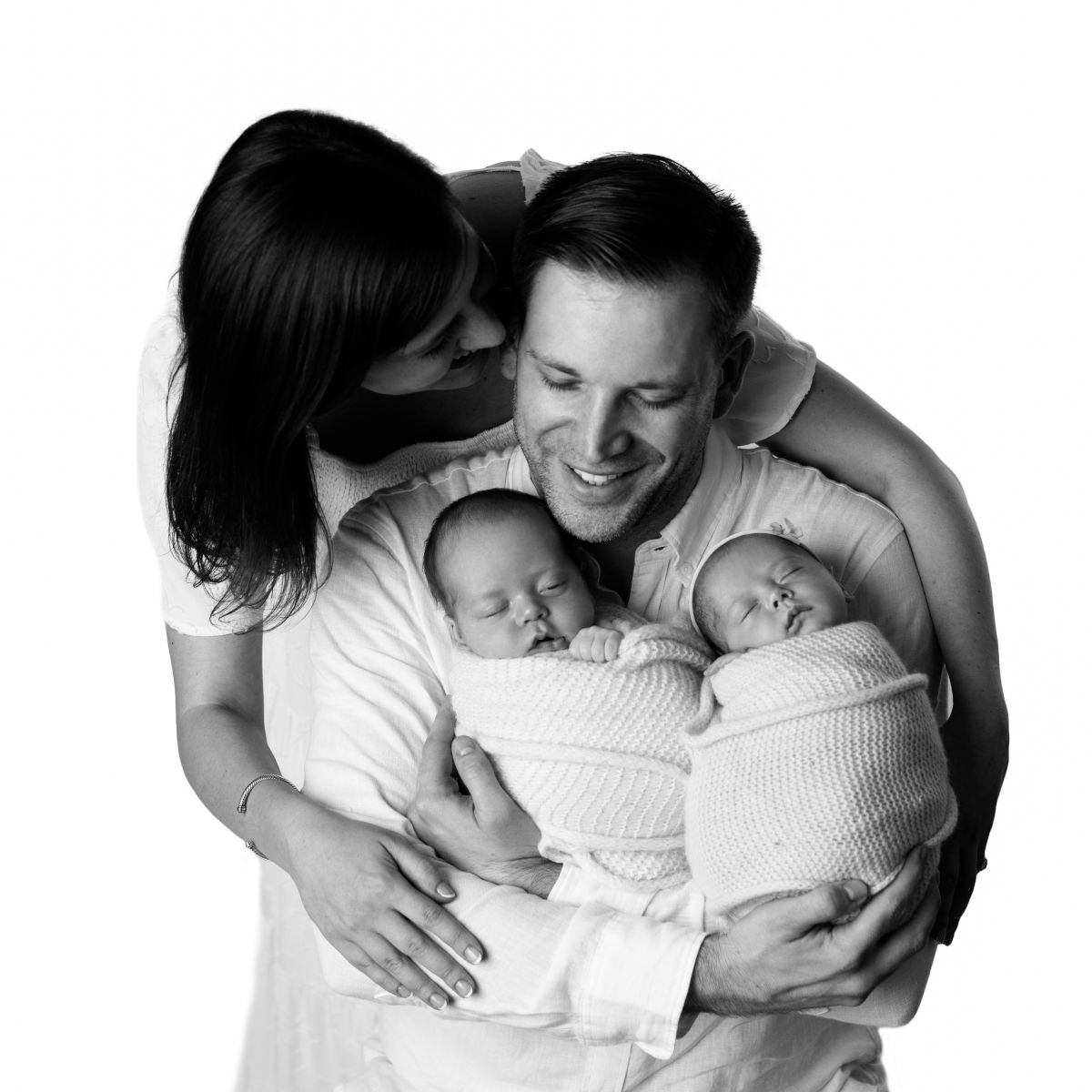 Parents holding sleeping twin newborn babies during a black and white family portrait session