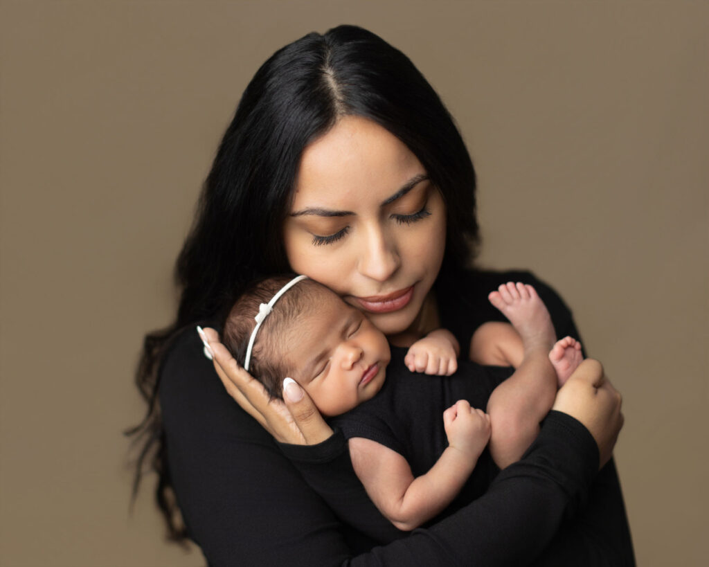 Mother gently holding her sleeping newborn baby during a professional studio portrait session