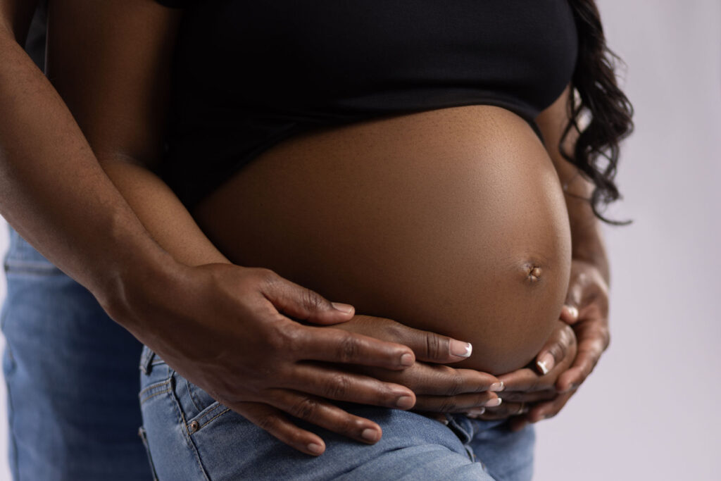 Close-up maternity portrait with parents gently holding a pregnant belly
