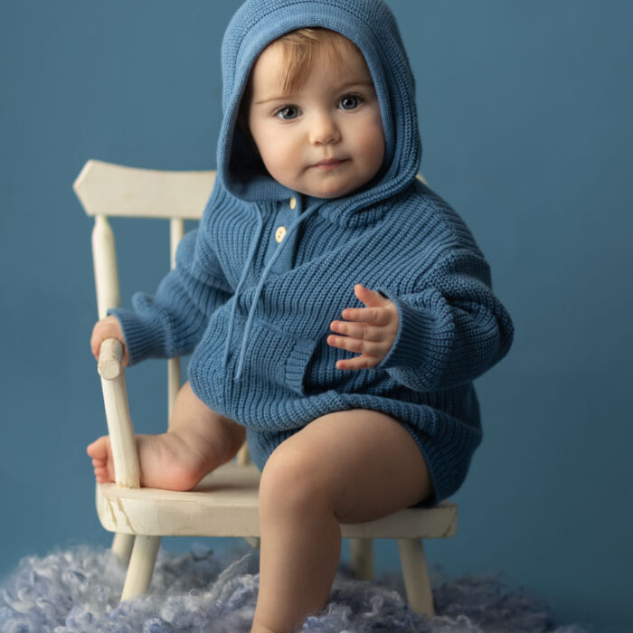 6 - month - old girl in blue knit hoodie during studio milestone session